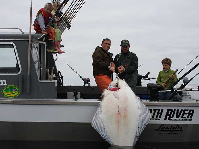 Charter fishing for halibut at Adventure Alaska, pulling a giant halibut on-board