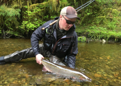 Fly-fishing with Adventure Alaska Southeast guided Alaska fly-fishing on Prince of Wales Island. Man holding steelhead on riverbank