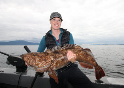 Guided saltwater fishing with Adventure Alaska Southeast on Prince of Wales Island Alaska. Drop dead gorgeous woman holding her catch, a ling cod caught near Thorne Bay Alaska