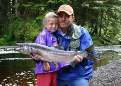 Alaska Salmon fishing and stream fishing with Adventure Alaska Southeast. Girl and father holing coho salmon on Alaska stream.