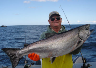 Fishing charters for King Salmon on Prince of Wales Island. Adventure Alaska fishing and hunting vacation packages in Thorne Bay on Prince of Wales Island. Man holds up his catch of a king salmon.